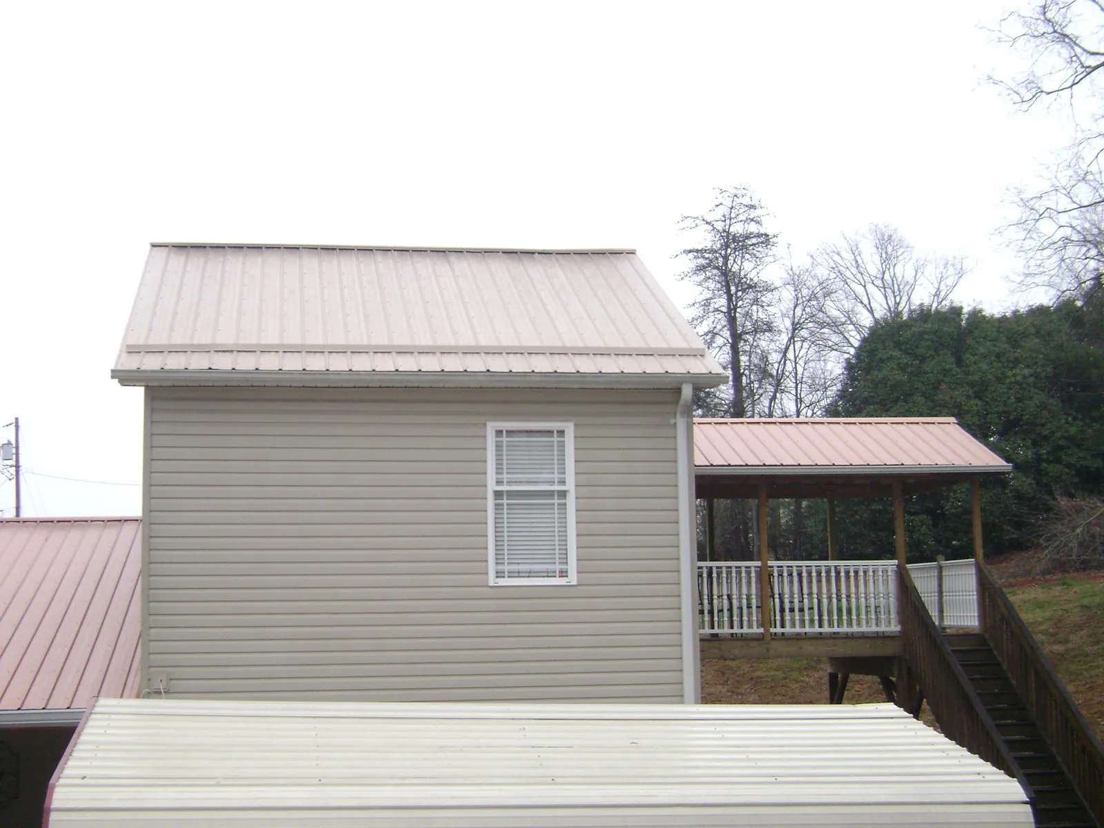 Tan metal roofs on a two story addition and attached porch, from a Roof Replacement job in North Springfield