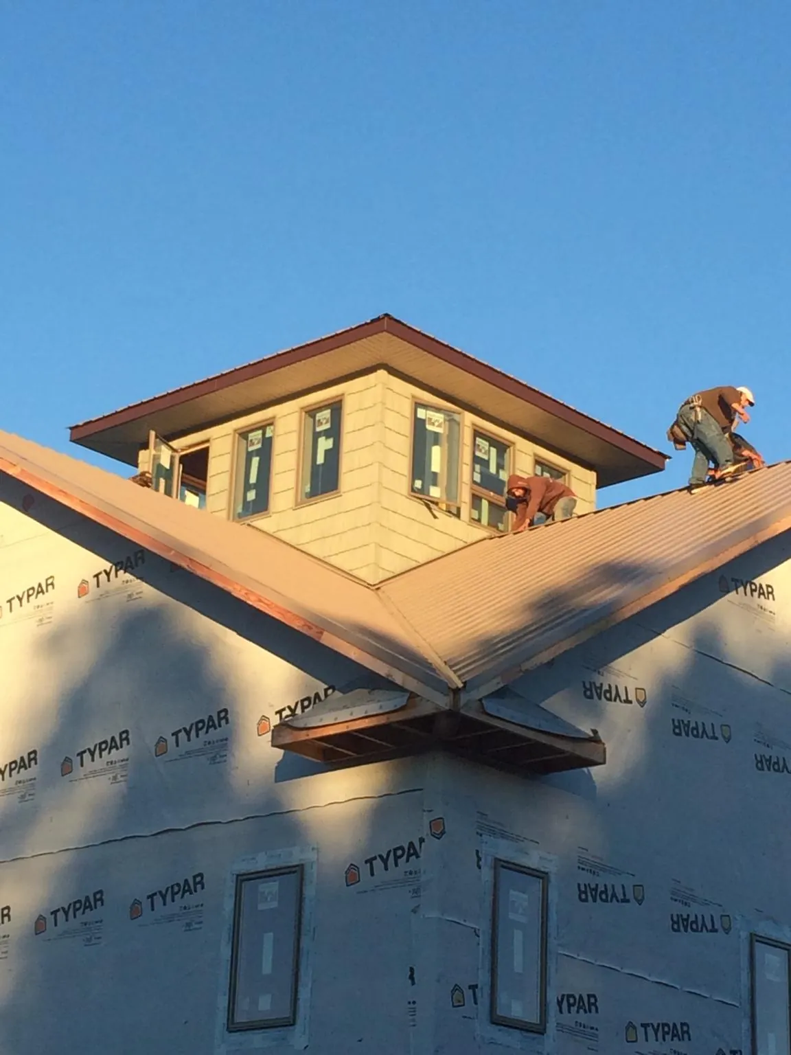 Roofers working around a rooftop cupola on a new metal roof at sunset — Roof Waterproofing in North Springfield by Roofing Brothers